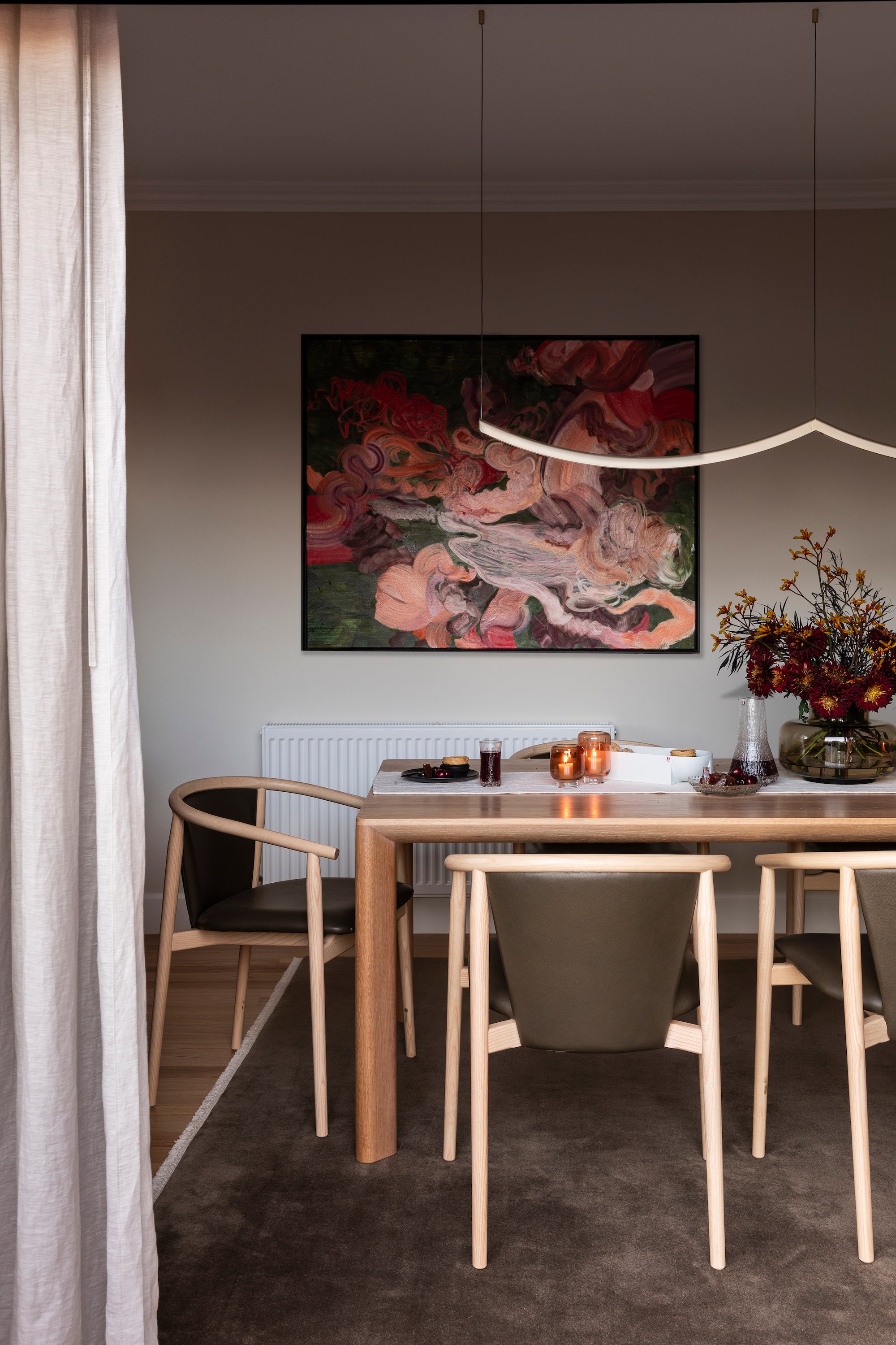 Dining room with a wooden table, chairs, and a colorful abstract painting on the wall.
