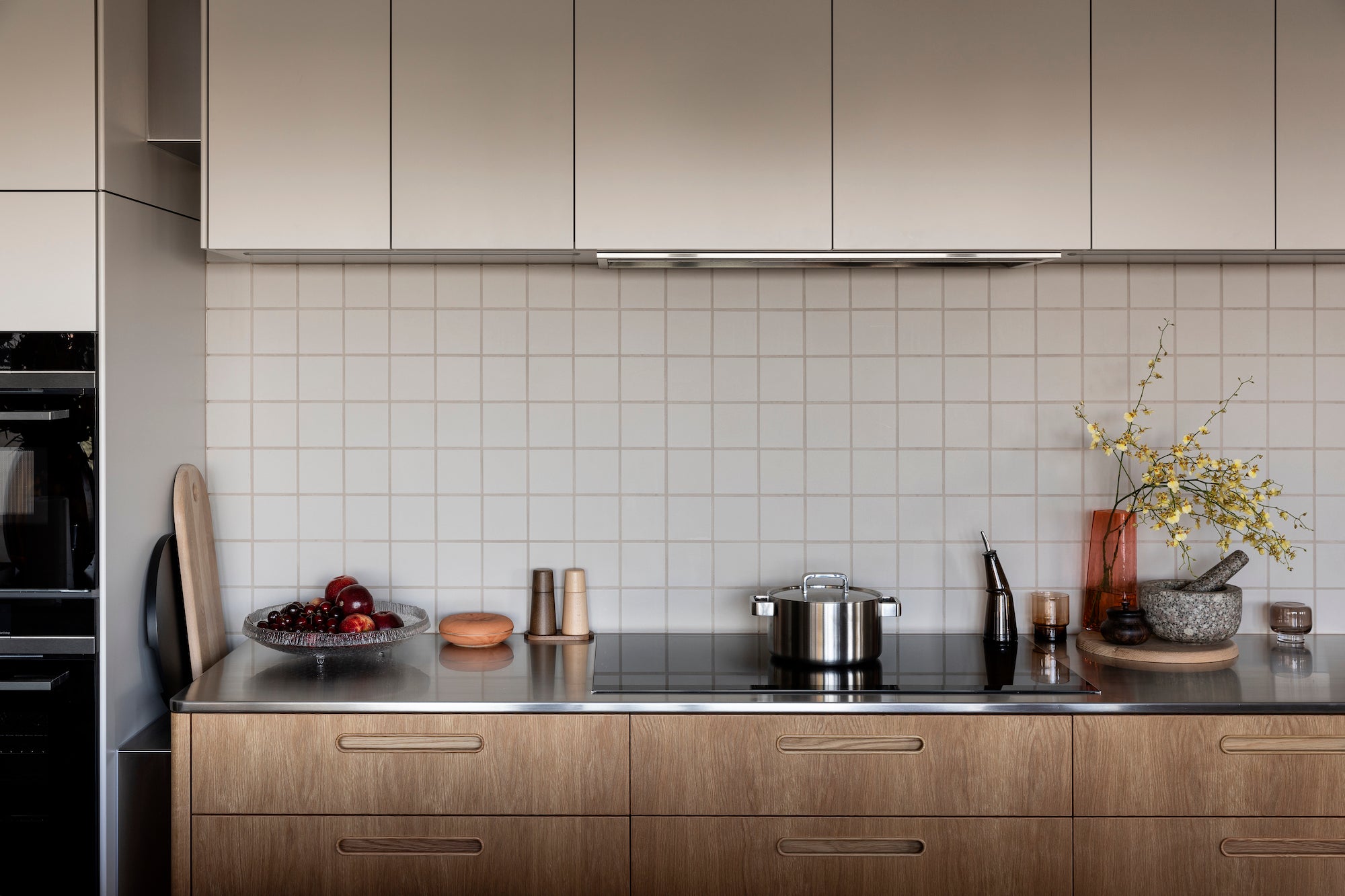 Modern kitchen with wooden cabinets, black stovetop, and decorative items.