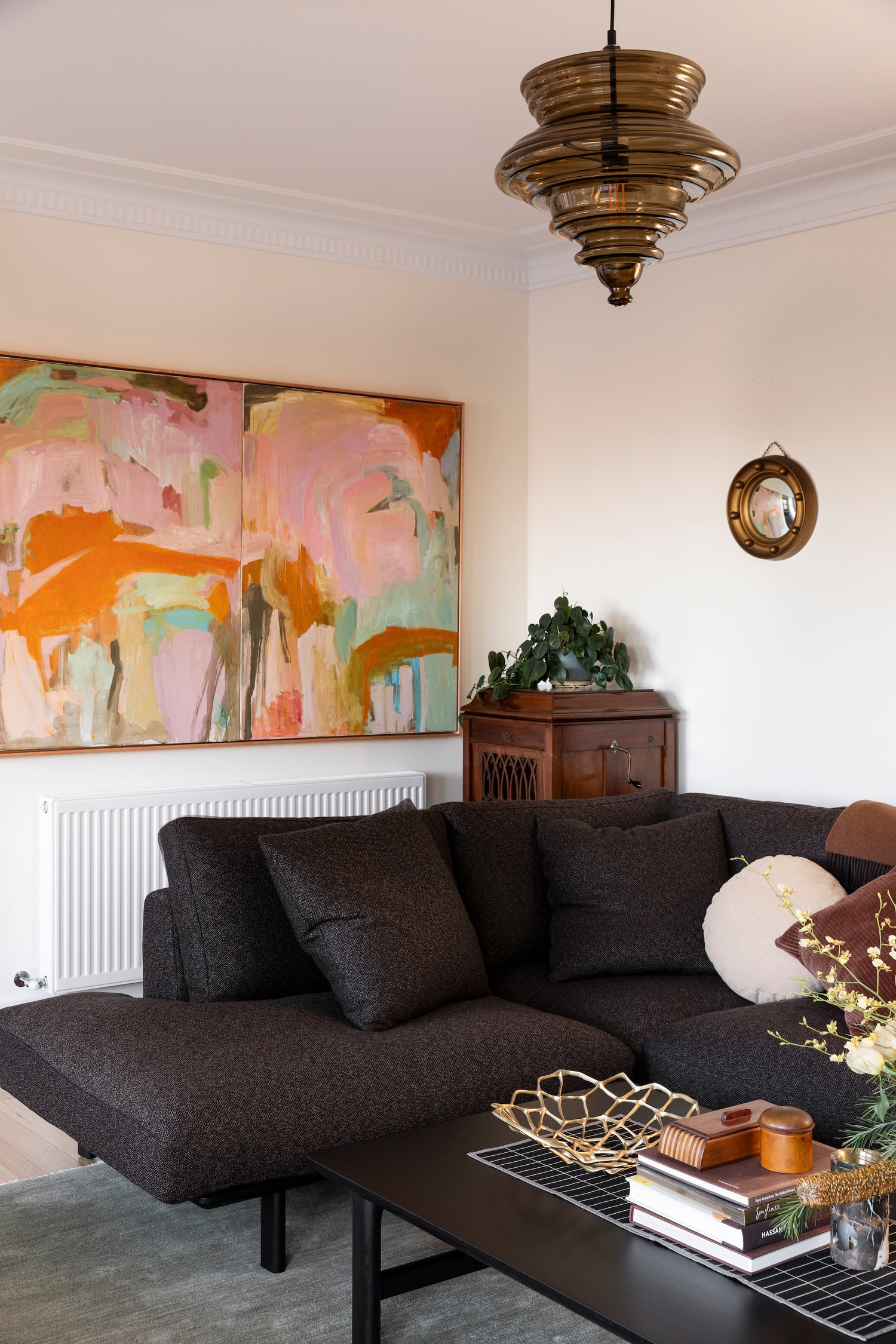 Living room with a dark gray sofa, abstract painting, and decorative items.